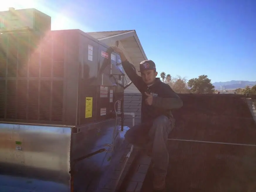 HVAC technician performing Air Duct Repair on a rooftop unit in Erie