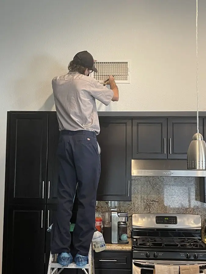 Technician inspecting an air vent during HVAC service in Erie